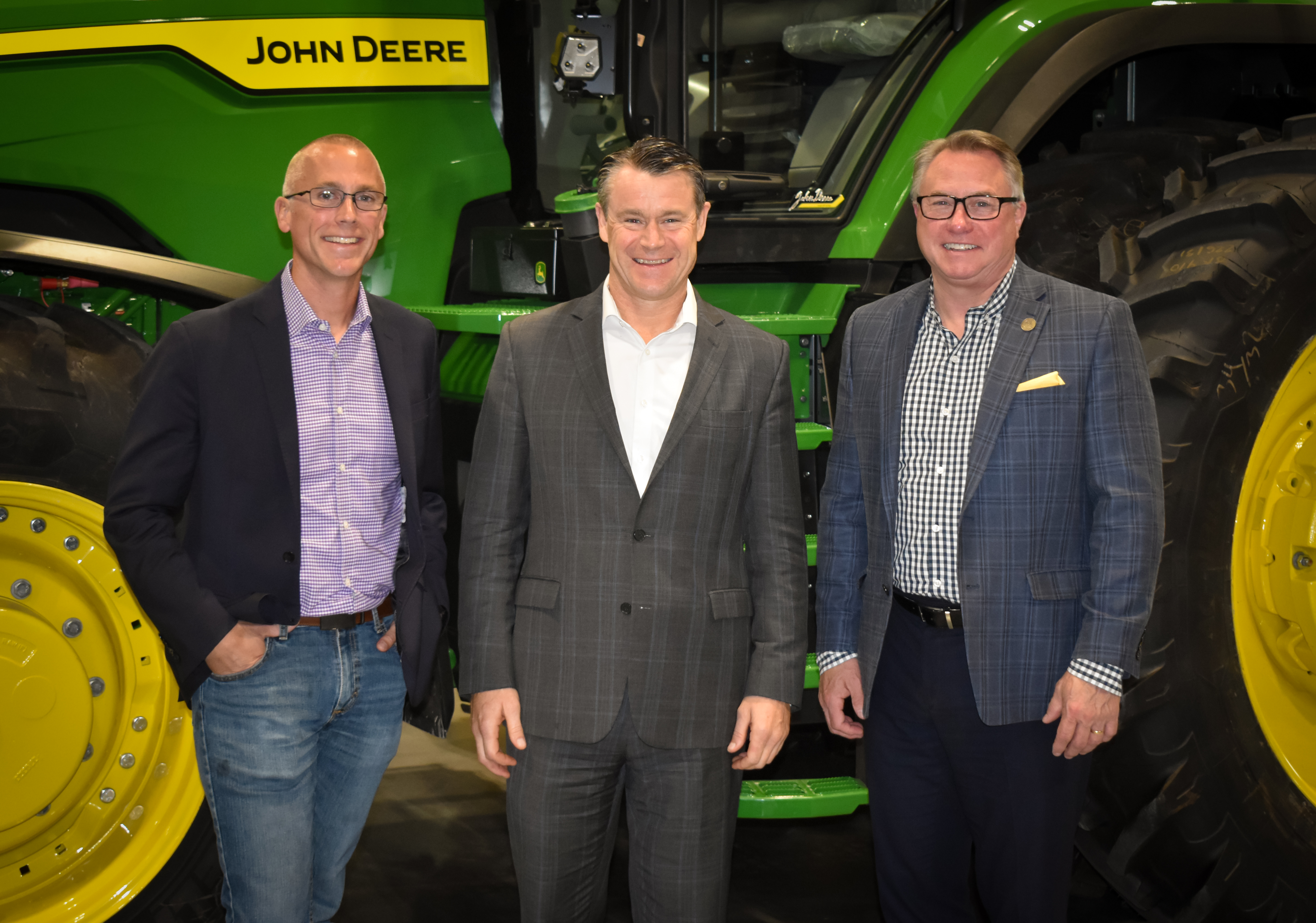 Mitch Frazier, Todd Young and Chuck Johnson standing in front of a green and yellow John Deere tractor.